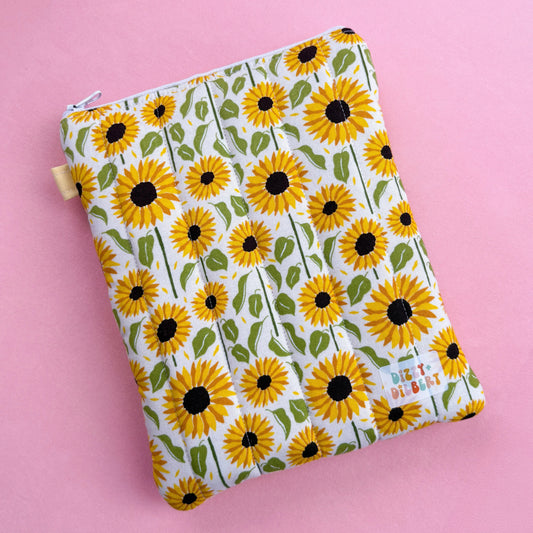 A white pouch with a yellow sunflower pattern printed on it, placed on a pink background.