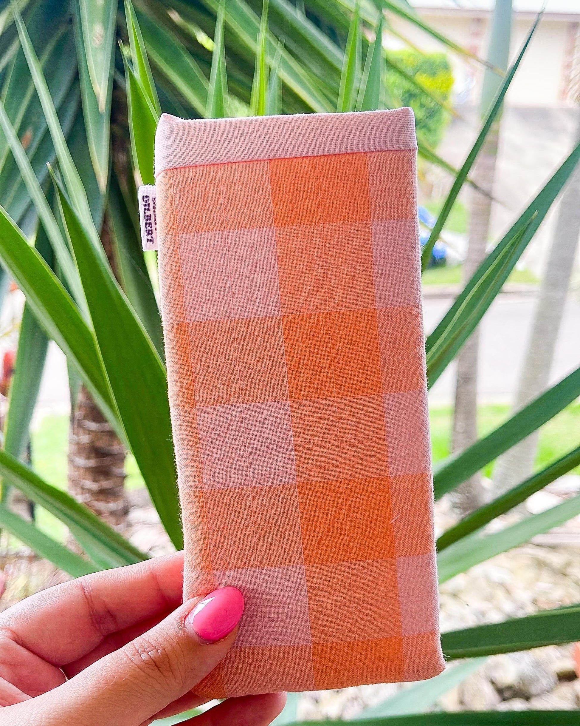 a hand holding a pink and orange checkered cloth